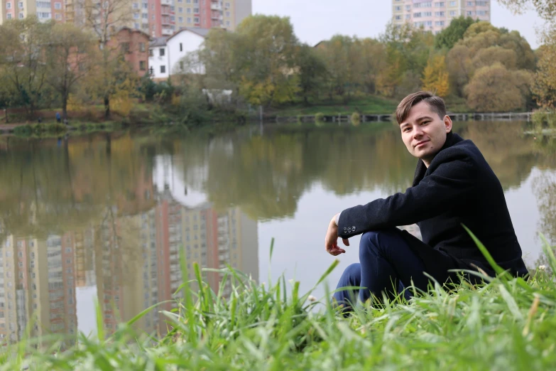 a man sitting next to a body of water, inspired by Fei Danxu, realism, park in background, avatar image, full frame image, professional profile picture