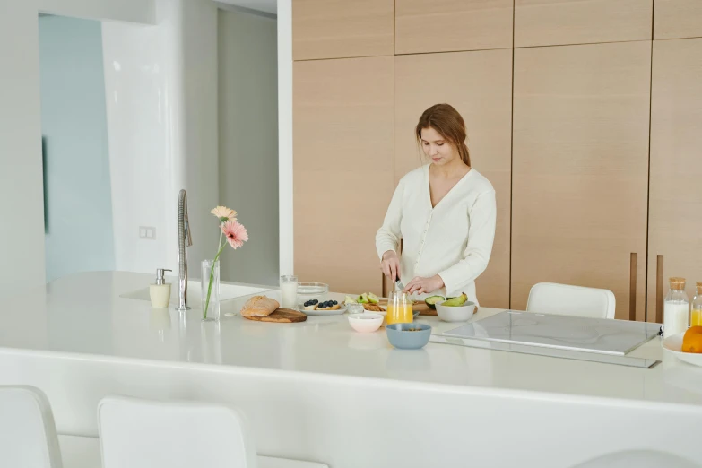 a woman standing in a kitchen preparing food, inspired by Caro Niederer, pexels contest winner, figuration libre, on a white table, sleek design, sitting at table, caucasian