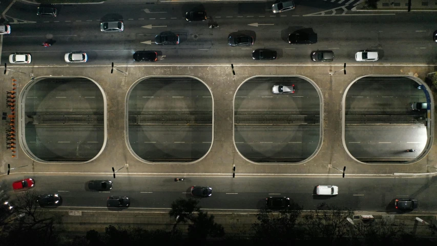 an aerial view of a parking lot at night, by Alejandro Obregón, hyperrealism, round windows, overpass, symmetrical image, instagram post