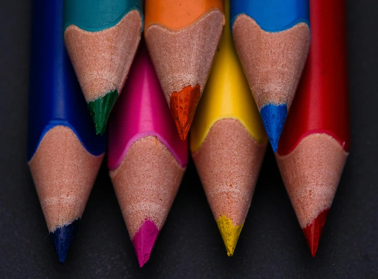 a group of colored pencils sitting next to each other, by Adam Marczyński, pexels contest winner, crayon art, deep colour, symmetrical image, with a black background, professional closeup photo