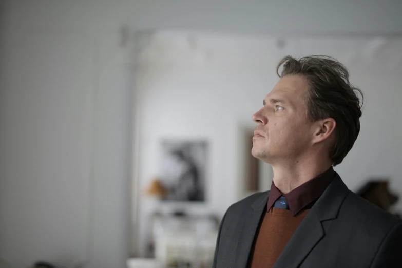 a man in a suit looking up into the sky, by Jørgen Roed, standing in corner of room, he is wearing a brown sweater, julian ope, profile image