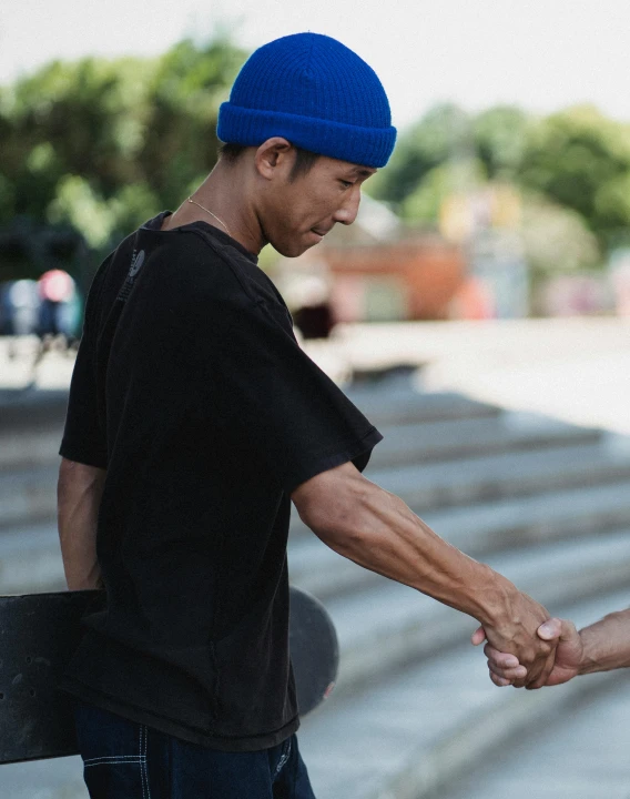 a couple of men standing next to each other holding hands, by Francis Helps, pexels contest winner, skateboarder style, half asian, wearing a backwards baseball cap, holding court