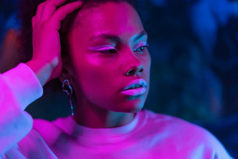 a woman with her hand on her head, inspired by Elsa Bleda, trending on pexels, afrofuturism, pink and blue lighting, innocent look. rich vivid colors, bisexual lighting, aida muluneh