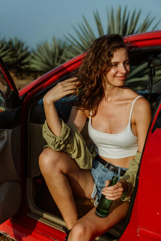 a woman sitting in the driver's seat of a red car, pexels contest winner, renaissance, wearing a tank top and shorts, flirting, curly haired, panoramic view of girl