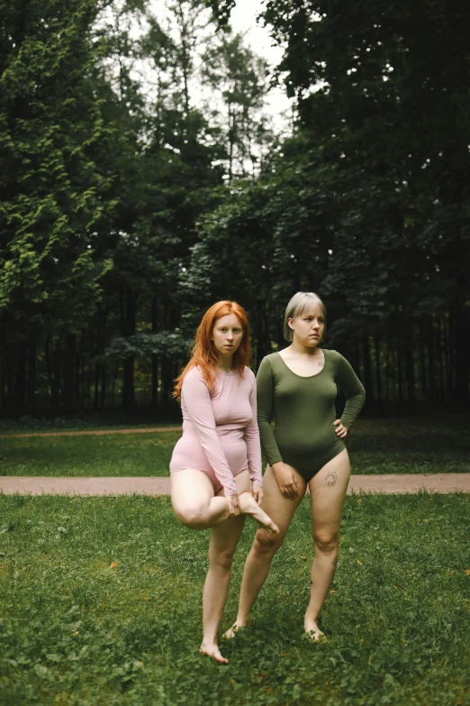 a couple of women standing on top of a lush green field, inspired by Vanessa Beecroft, unsplash, renaissance, muted colored bodysuit, round thighs, at a park, ( redhead