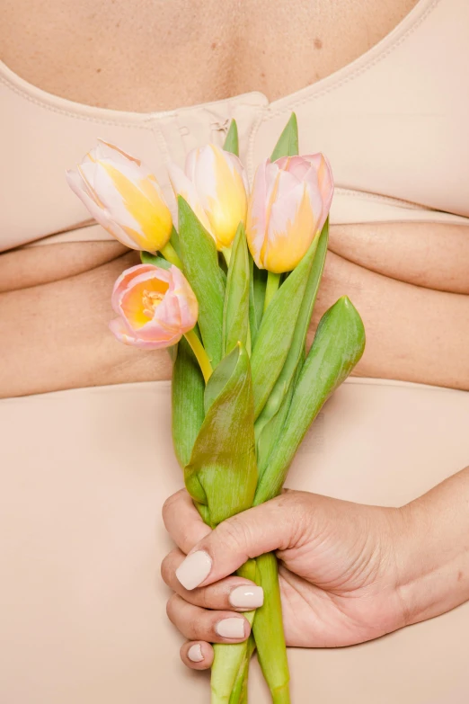 a pregnant woman holding a bouquet of tulips, an album cover, shutterstock contest winner, in shades of peach, synthetic skin, detail shot, with arms bare