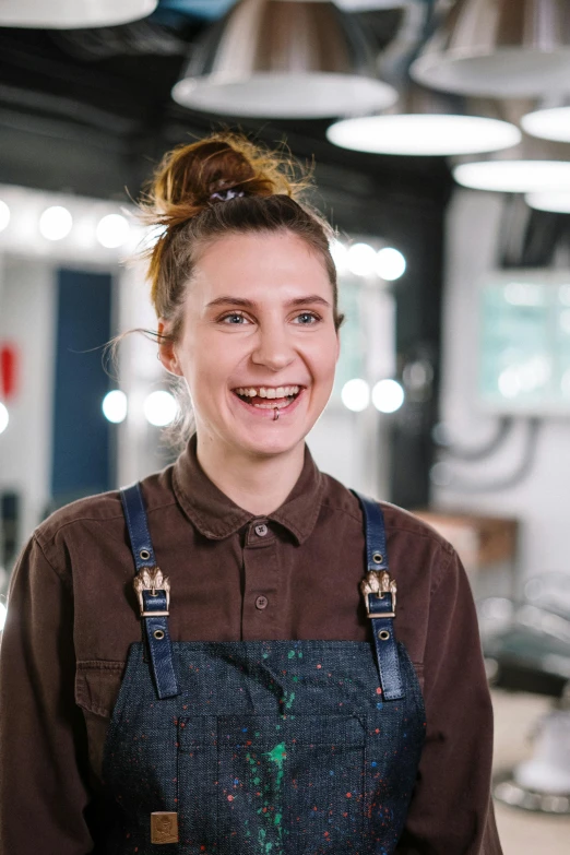 a woman that is standing in a room, wearing overalls, hair styled in a bun, adafruit, happy chef