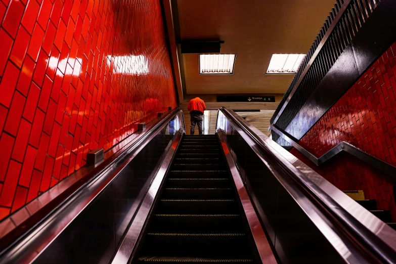 a person riding an escalator down a set of stairs, an album cover, inspired by Rodolfo Escalera, unsplash, hyperrealism, red scales, subway station, orange and black, 🦩🪐🐞👩🏻🦳
