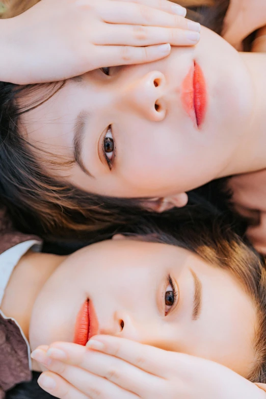 a couple of women laying on top of a bed, an album cover, inspired by Wang Duo, trending on pexels, wan adorable korean face, closeup headshot portrait, twins, orange pupils