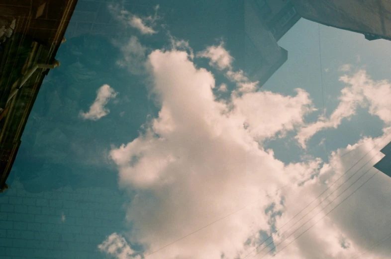 a couple of buildings that are next to each other, a picture, inspired by Elsa Bleda, unsplash, magical realism, girl clouds, clear glass wall, rinko kawauchi, partly cloudy