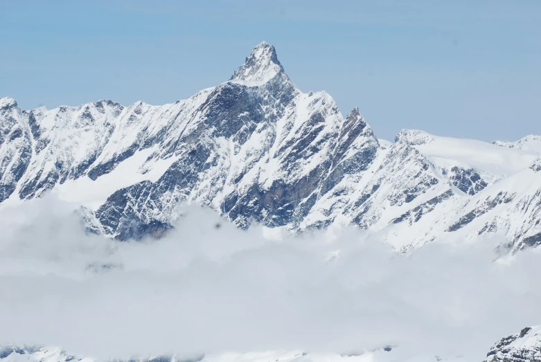 a group of people riding skis on top of a snow covered slope, an album cover, by Werner Andermatt, pexels contest winner, giant imposing mountain, spire, seen from a distance, herzog de meuron