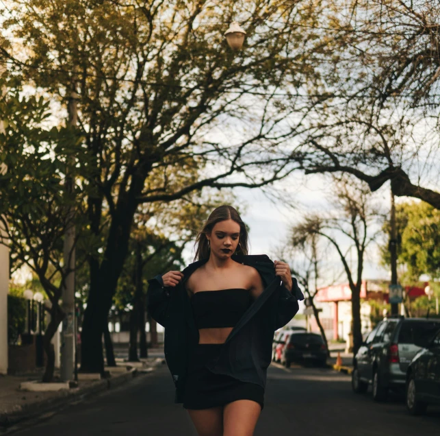 a woman riding a skateboard down a street, an album cover, inspired by Elsa Bleda, pexels contest winner, realism, bra and shorts streetwear, sydney sweeney, forest city streets behind her, model posing