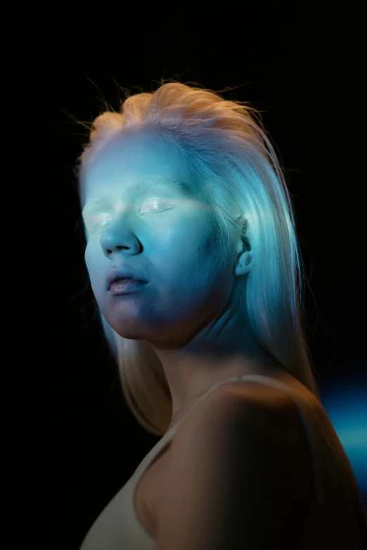 a woman with blue light on her face, a hologram, inspired by Gottfried Helnwein, trending on pexels, portrait of albino mystic, louise zhang, young blonde woman, full view of face and body