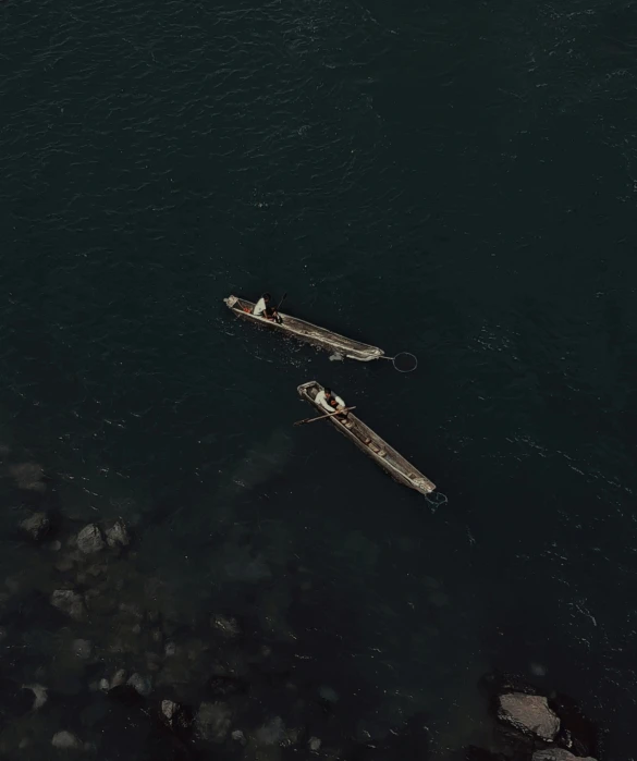 a couple of boats floating on top of a body of water, by Attila Meszlenyi, 4 k cinematic photo, a high angle shot, battered, dark