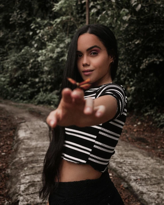 a woman pointing her finger at the camera, by reyna rochin, wearing a crop top, butterfly, gif, low quality photograph