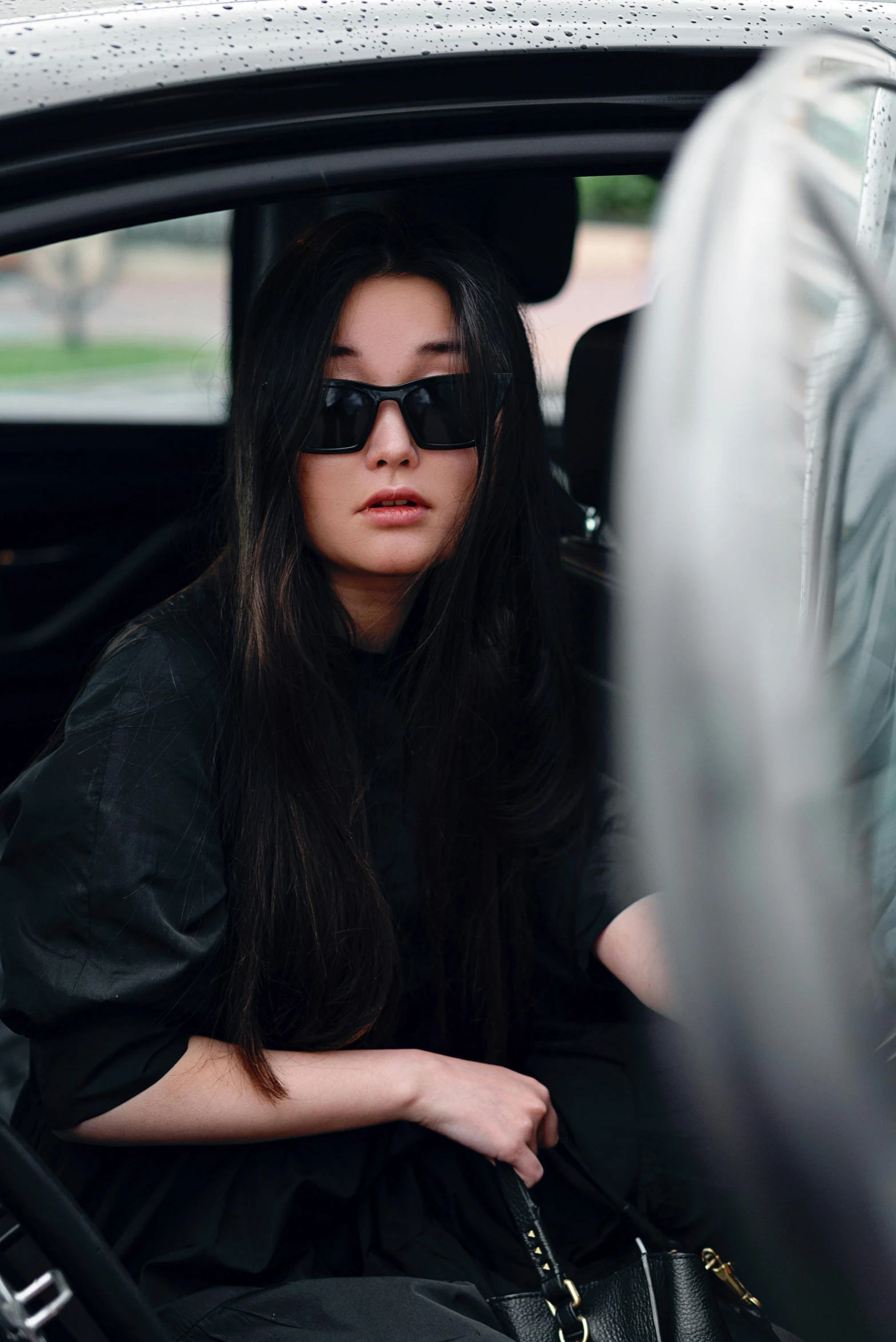 a woman sitting in the passenger seat of a car, an album cover, inspired by Wang E, trending on pexels, bella poarch, casual black clothing, pouty, designer sunglasses