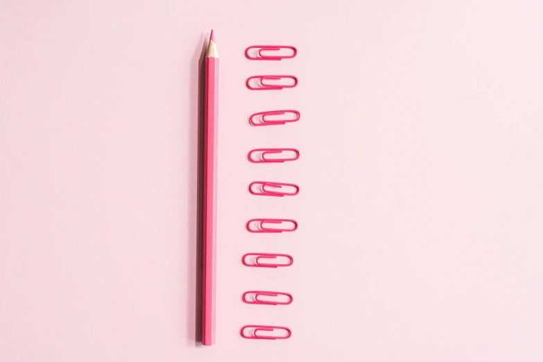 a pencil and paper clips on a pink background, by Adam Marczyński, trending on pexels, ffffound, body shot, red, lined up horizontally