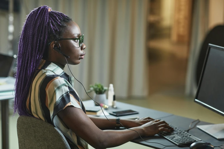 a woman sitting at a desk using a computer, by Julia Pishtar, trending on pexels, afrofuturism, wearing purple headphones, worksafe. instagram photo, mit technology review, cinematic shot