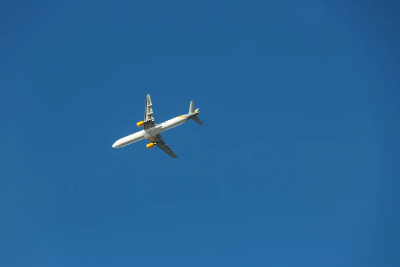 a large jetliner flying through a blue sky, by Peter Churcher, pexels contest winner, minimalism, white and yellow scheme, hunting, 4 0 9 6, decoration