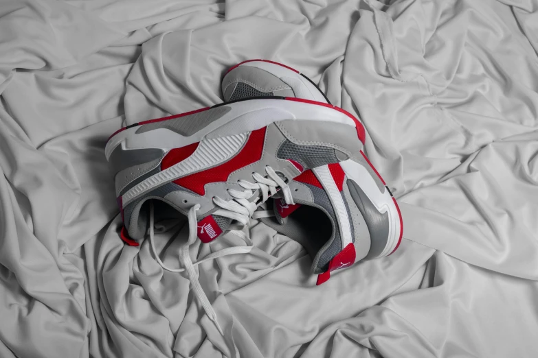 a pair of sneakers sitting on top of a bed, a picture, red and grey only, puma, zoomed out shot, isometric view
