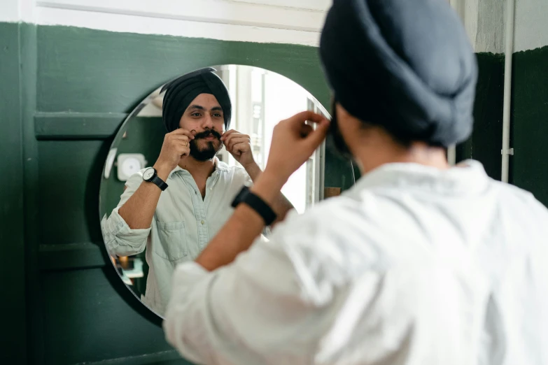 a man brushing his teeth in front of a mirror, inspired by Manjit Bawa, pexels contest winner, wearing a turban, round jawline, doctors mirror, lachlan bailey