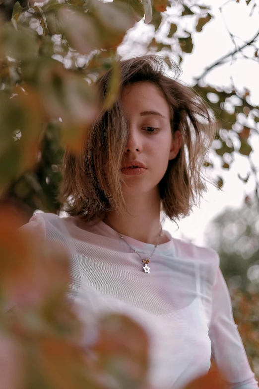 a woman standing under a tree with her eyes closed, an album cover, inspired by Elsa Bleda, trending on pexels, happening, wearing several pendants, kiko mizuhara, grainy footage, portrait image