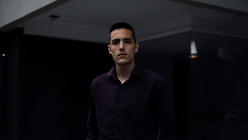 a man in a purple shirt and black pants, a character portrait, by Alejandro Obregón, pexels contest winner, around 1 9 years old, serious business, indoor picture, slightly pixelated