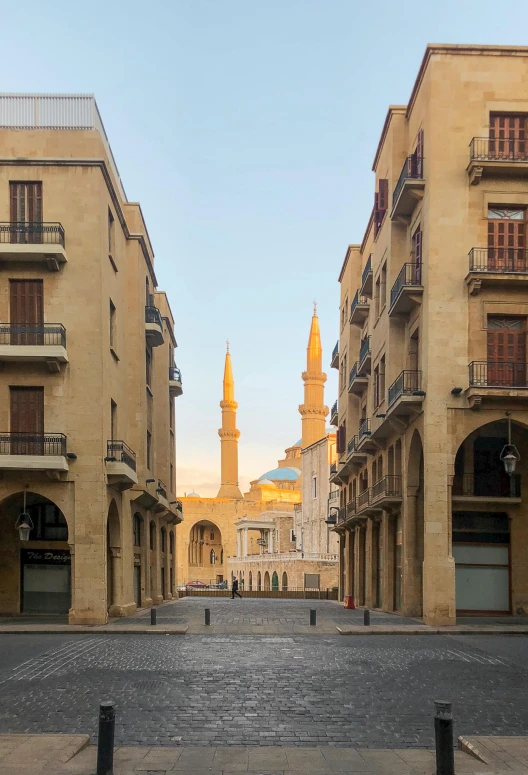 a street with buildings and a clock tower in the distance, neoclassicism, arabic architecture, golden towers, farid ghanbari, seen from afar