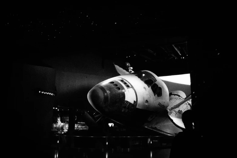 a black and white photo of a space shuttle, a black and white photo, shot on iphone 6, background is a low light museum, nostalgic 8k, atlantis