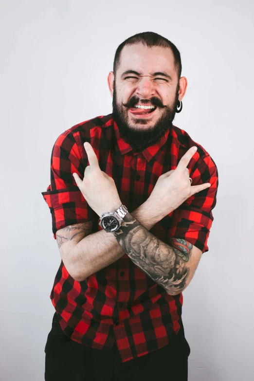 a man with a beard wearing a red and black shirt, a tattoo, inspired by Camilo Egas, trending on pexels, goofy smile, flannel, studio photo, lgbtq