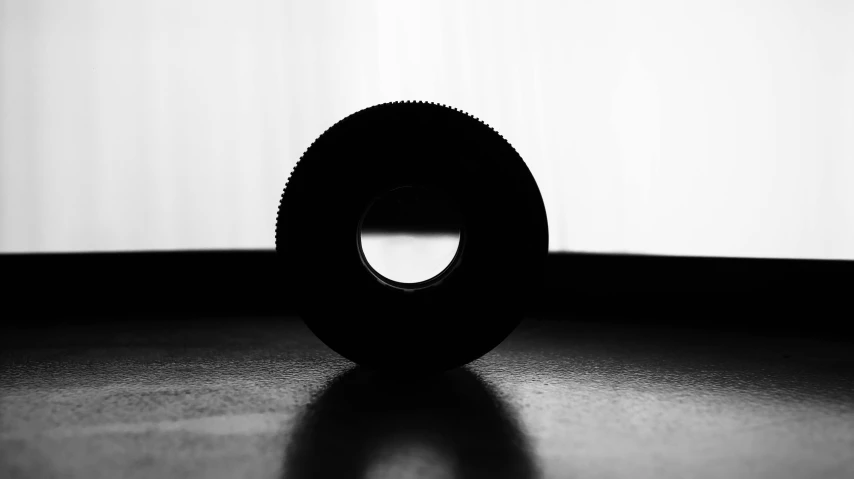 a black and white photo of a tire on a floor, a black and white photo, by Adam Chmielowski, minimalism, silhouette :7, bokeh macro lens, the ring, product introduction photo