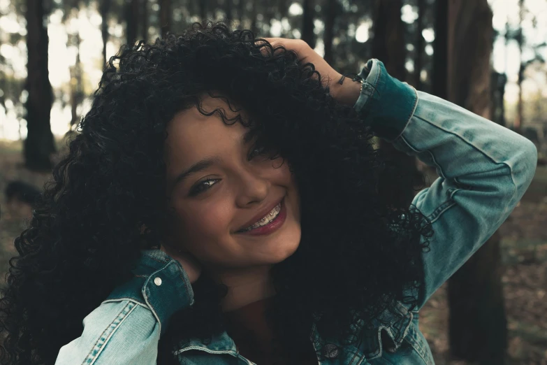 a close up of a person wearing a denim jacket, pexels contest winner, dark short curly hair smiling, avatar image, long wild black curly hair, cute girls
