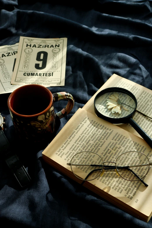 an open book sitting on top of a bed next to a magnifying glass, a still life, by Nazmi Ziya Güran, pexels, photorealism, portrait of a detective, coffee cup, 1 9 2 0's, 35mm —w 1920 —h 1080