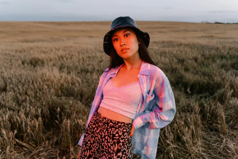 a woman standing in a field wearing a hat, trending on pexels, charli xcx, cropped shirt with jacket, glowing aesthetic, pastel clothing