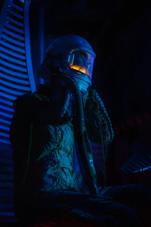 a man in a helmet talking on a cell phone, a hologram, inspired by ridley scott, afrofuturism, extremely moody blue lighting, wearing astronaut outfit, alien room, photograph of a techwear woman