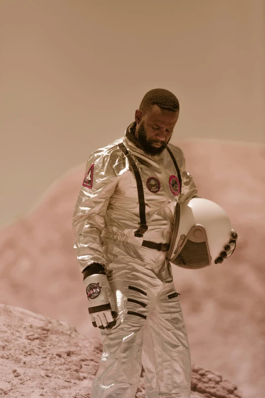 a man in a space suit holding a helmet, pexels contest winner, afrofuturism, kevin hart, cinematic still frame, moon behind him, brown skin like soil