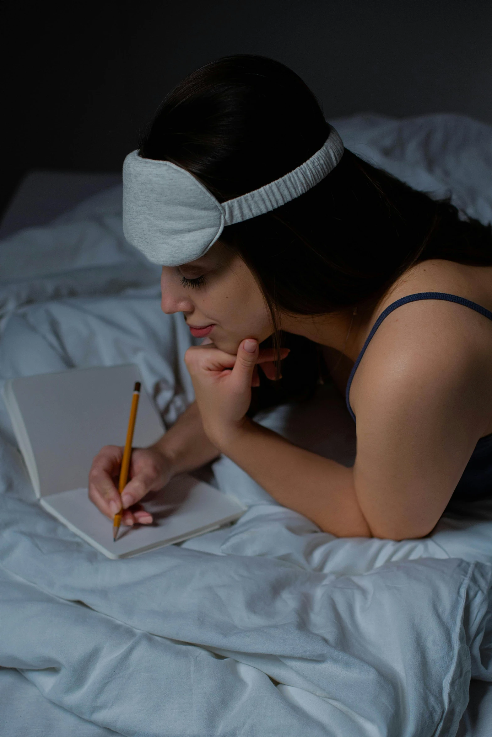 a woman laying on a bed with a notebook and a pencil, trending on reddit, renaissance, blindfold, portrait soft low light, high-quality photo, profile image