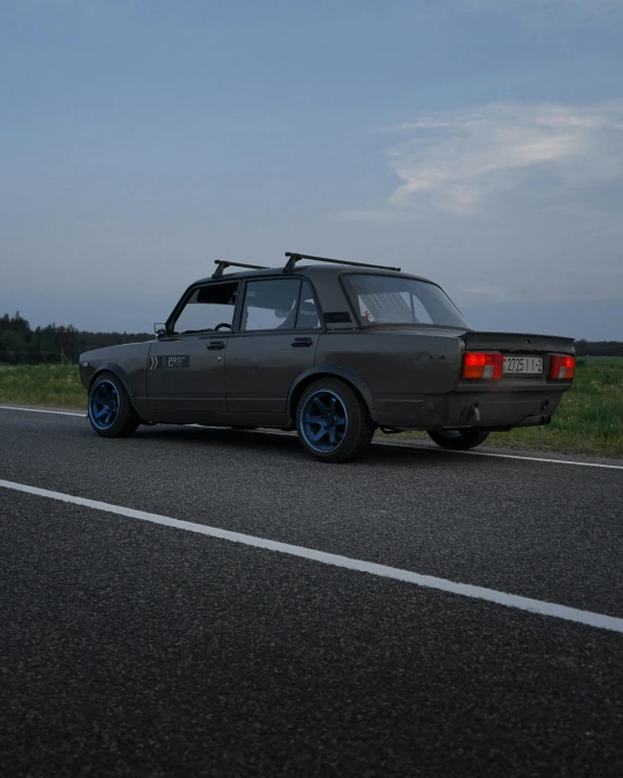 a car that is sitting on the side of the road, by Attila Meszlenyi, lada car, strong rim light, grey, late summer evening