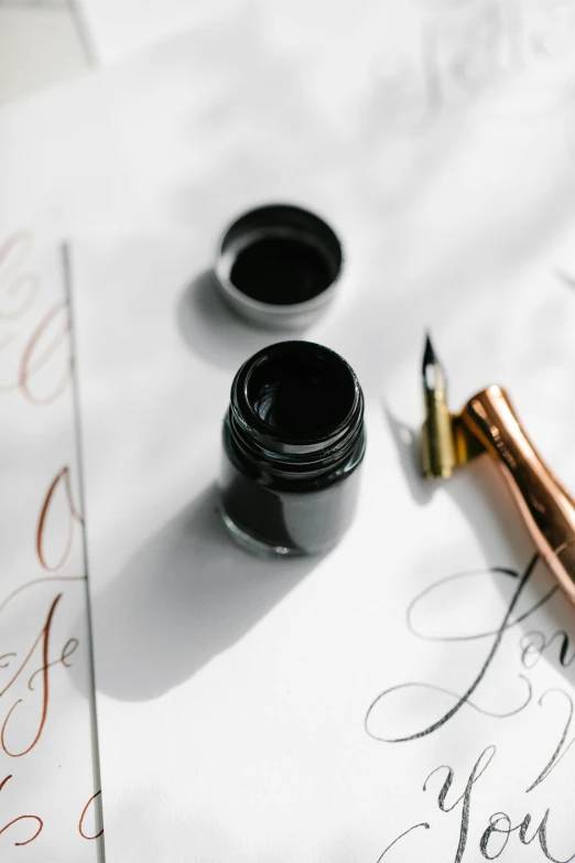 a fountain pen sitting on top of a piece of paper, black paint, black and terracotta, in love, calligraphy