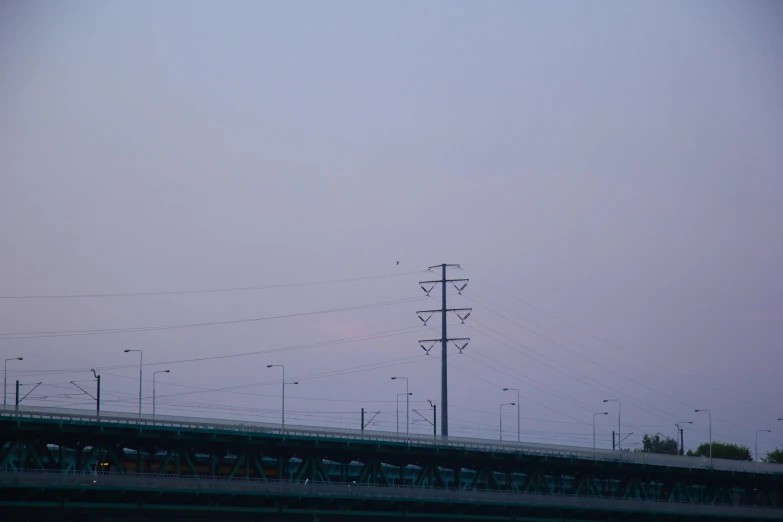 a bridge over a body of water under a cloudy sky, an album cover, by Attila Meszlenyi, postminimalism, pink violet light, telephone wires, 2022 photograph, streetlamps