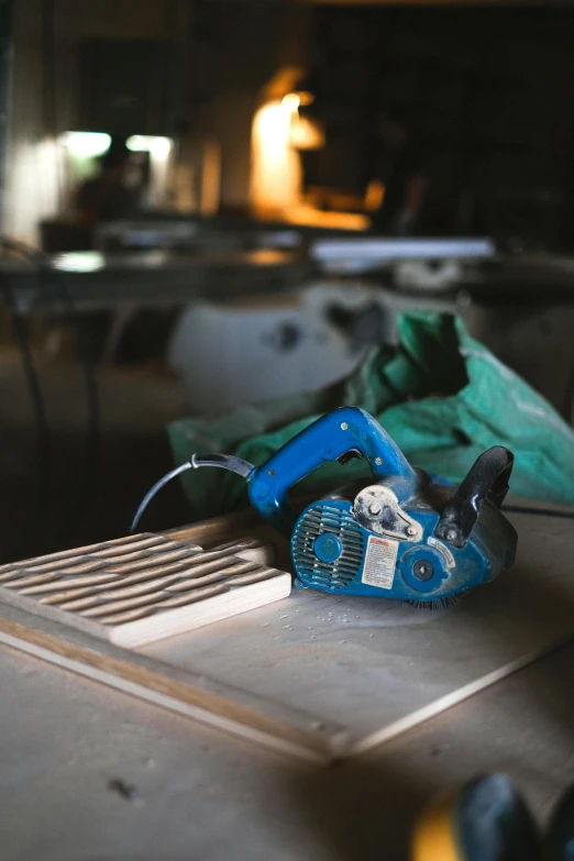 a blue blower sitting on top of a wooden table, pexels contest winner, arbeitsrat für kunst, holding wood saw, factory floor, thumbnail, iconic scene