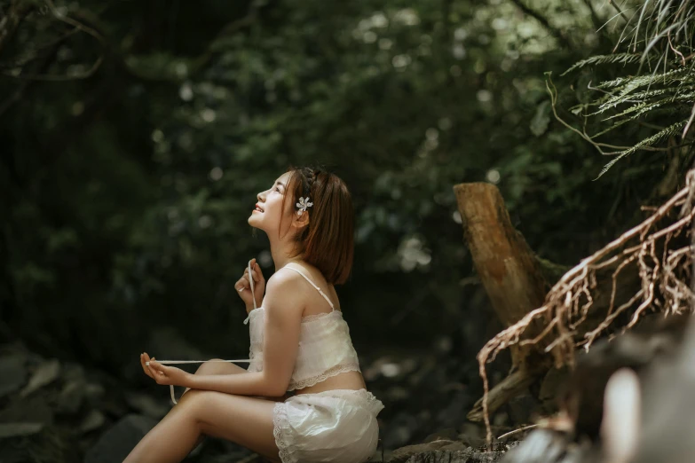 a woman sitting on a rock in a forest, an album cover, pexels contest winner, flirting, asian female, listening to music, good lighted photo