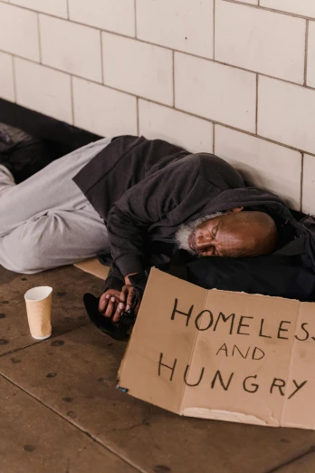 a homeless person laying on the ground with a sign that says homeless and hungry, a photo, trending on unsplash, renaissance, mukbang, dave chappelle, photo of a 50-year-old white man, profile image