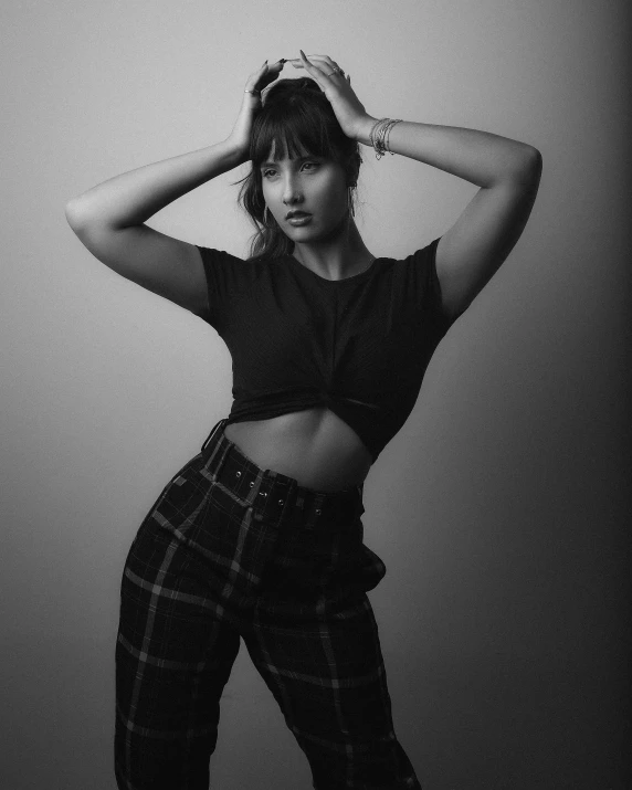 a black and white photo of a woman in plaid pants, unsplash, realism, she has black hair with bangs, wearing a sexy cropped top, beauty expressive pose, various poses shooting photos