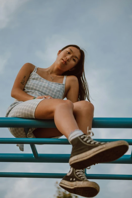 a woman sitting on top of a blue bench, trending on pexels, happening, wearing a camisole and shorts, looking up at the camera, flannel, bella poarch