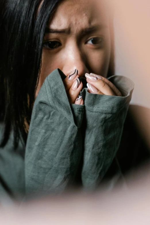 a woman covers her face with her hands, trending on pexels, long sleeves, young asian woman, unclipped fingernails, subdued colors