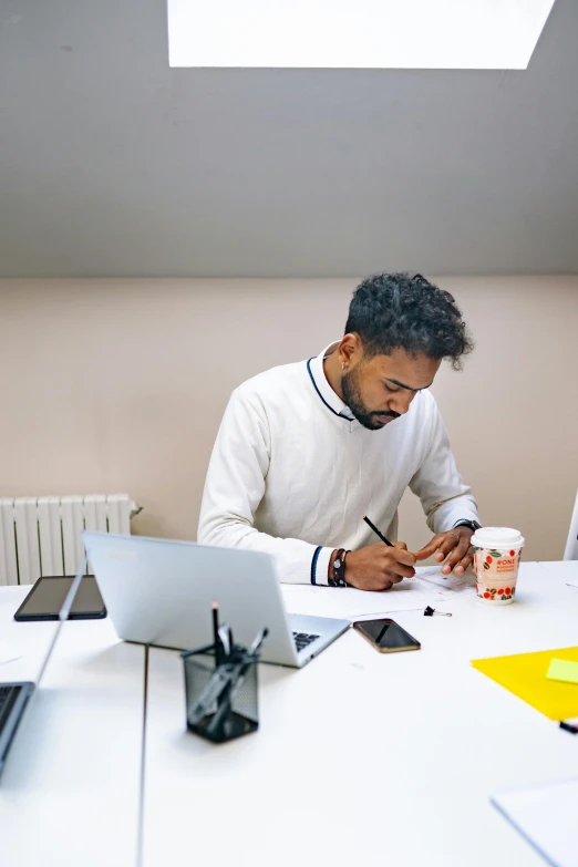 a man sitting at a table working on a laptop, pexels contest winner, arbeitsrat für kunst, writing on a clipboard, riyahd cassiem, in an office, jayison devadas