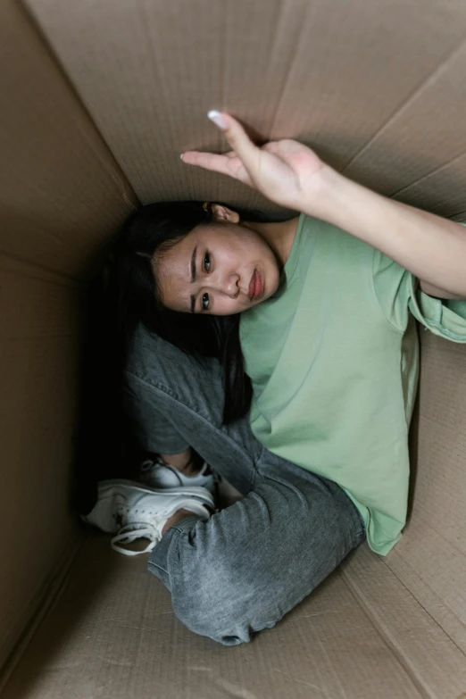 a woman is sitting in a cardboard box, inspired by Elsa Bleda, pexels contest winner, renaissance, falling out of the face, asian girl, high angle, recovering from pain