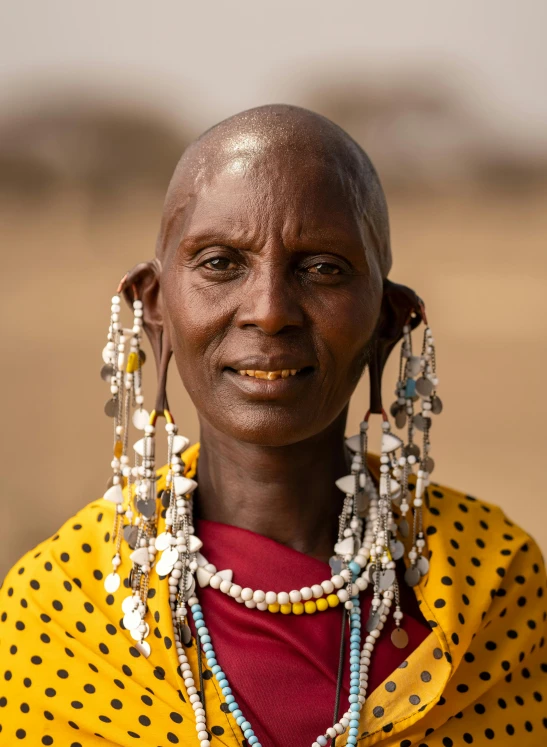 a close up of a person wearing a yellow shirt, hurufiyya, masai, long earrings, avatar image, high resolution photo