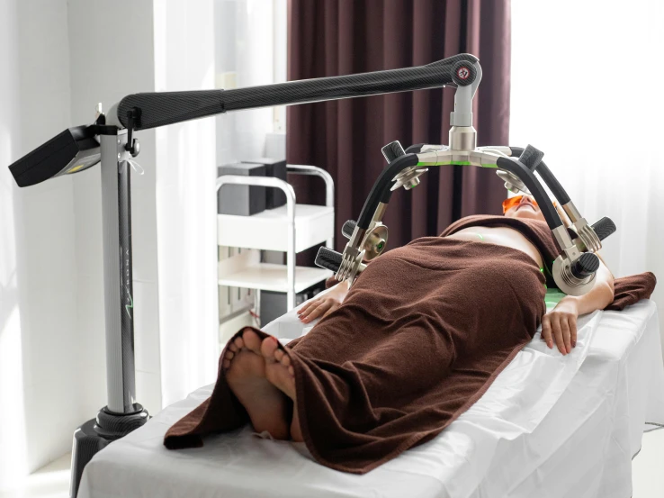 a person laying on a bed in a room, mechanical arm, spa, healthcare, still photograph